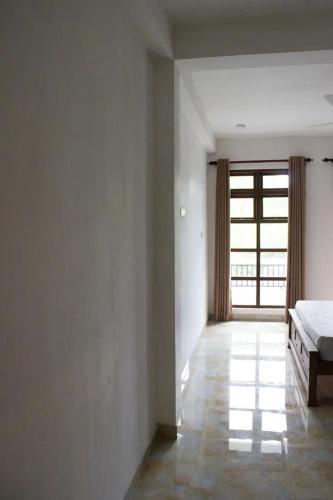 an empty room with a bed and a window at URALSURF HOUSE in Weligama