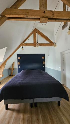 a bedroom with a blue bed in a attic at Domaine Caloin - SPA in Echinghen