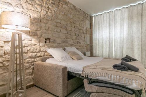 une chambre avec un lit et un mur en pierre dans l'établissement Cosy appartement Paris 20e, à Paris