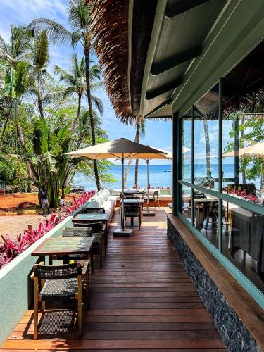 a wooden deck with tables and umbrellas on the beach at Bom Bom - Principe Collection in Principe