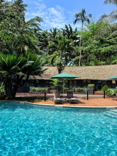 a swimming pool with a table and a green umbrella at Bom Bom - Principe Collection in Principe