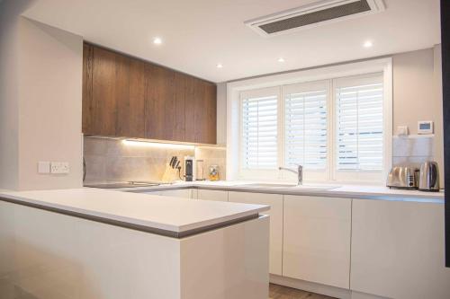 a kitchen with white counters and wooden cabinets at Stunning Rare Soho Gem in London