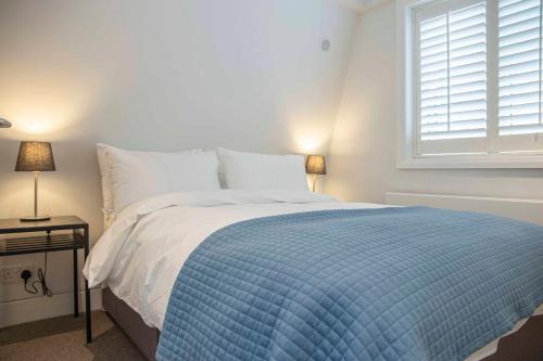 a bedroom with a bed with a blue comforter and a window at Stunning Rare Soho Gem in London