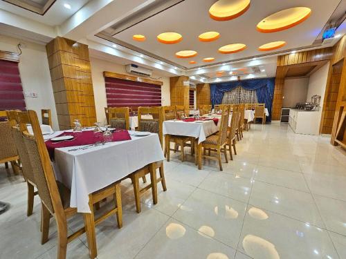 a restaurant with white tables and wooden chairs at Hotel Safa Residency - DHAKA in Dhaka