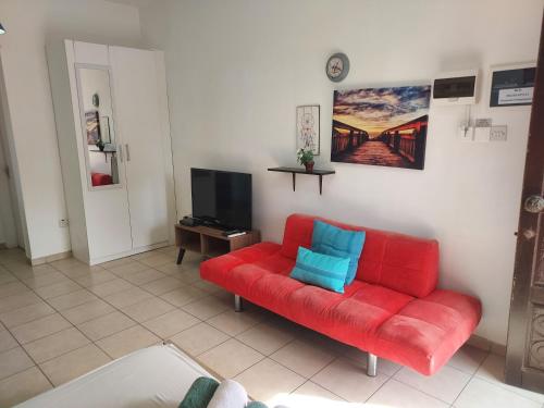 a living room with a red couch and a tv at Magic Sea Apartments in Larnaka