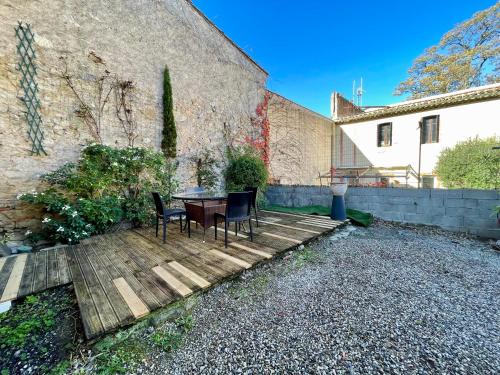 a wooden deck with chairs and a table in front of a building at Côté Cité appartements - Parking privé - 100m Cité médiévale in Carcassonne