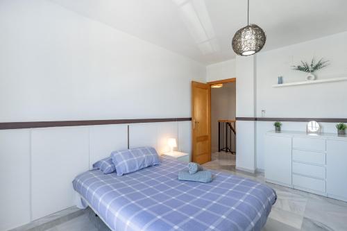 a bedroom with a blue bed and a kitchen at Chalet con piscina a 10 minutos de Granada in Ogíjares