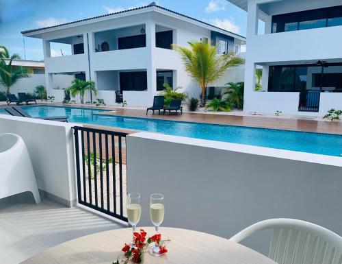 a table with wine glasses on a balcony with a swimming pool at Oasis luxury apartment in Jan Thiel - close to the beach in Jan Thiel