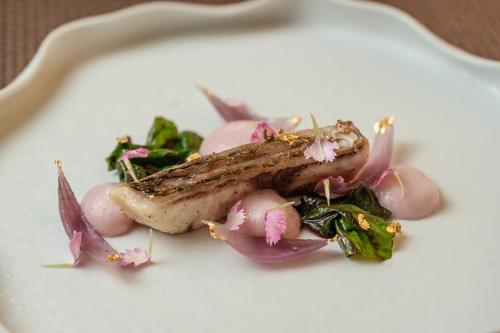 a white plate with a piece of meat and vegetables at Villa Neri Resort & Spa in Linguaglossa