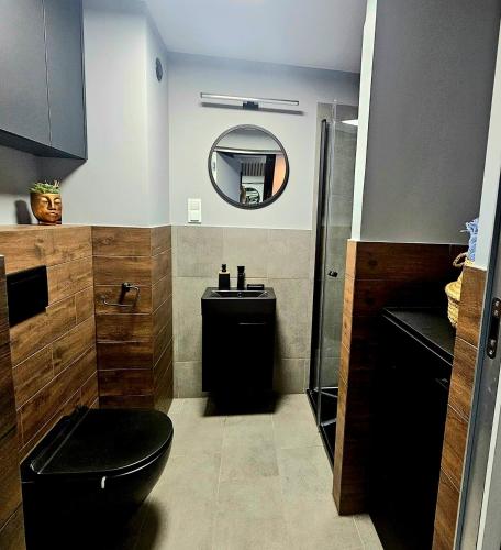 a bathroom with a black toilet and a mirror at Apartament Wrocław Promenady in Wrocław
