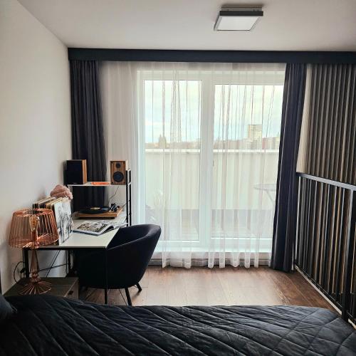a bedroom with a bed and a desk and a window at Apartament Wrocław Promenady in Wrocław
