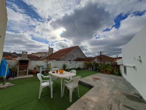 a patio with a table and chairs on the grass at Vivenda do Américo in Juncal