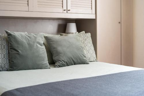 a bed with grey and white pillows and a cabinet at Private Jacuzzi - Villa Bellosguardo in Florence Historic Center in Florence