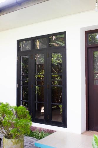a black door on the side of a white house at URALSURF HOUSE in Weligama