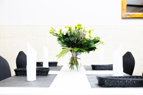 a vase of flowers on a table with chairs at Hotel ARDEN in Środa Śląska