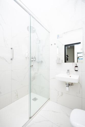 a white bathroom with a shower and a sink at Hotel ARDEN in Środa Śląska