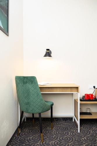 a green chair sitting in front of a desk at Hotel ARDEN in Środa Śląska