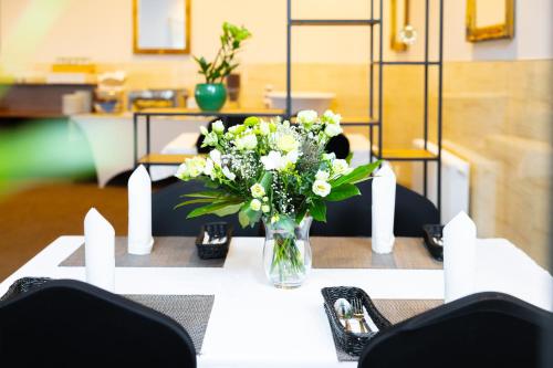 a vase of white flowers sitting on a table at Hotel ARDEN in Środa Śląska
