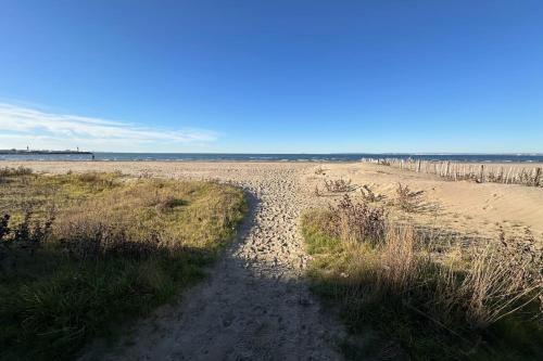 un chemin de terre menant à une plage de sable. dans l'établissement Côté Mer - Appartement vue mer en première ligne, au Grau-du-Roi