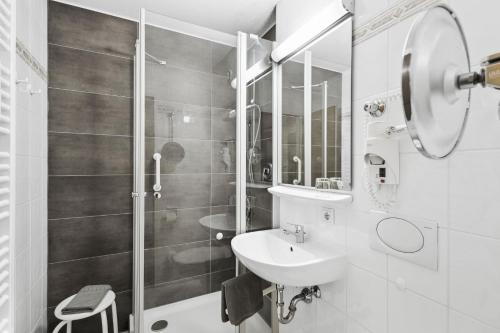 un bagno bianco con lavandino e doccia di Appartementhaus Bavaria a Bad Füssing