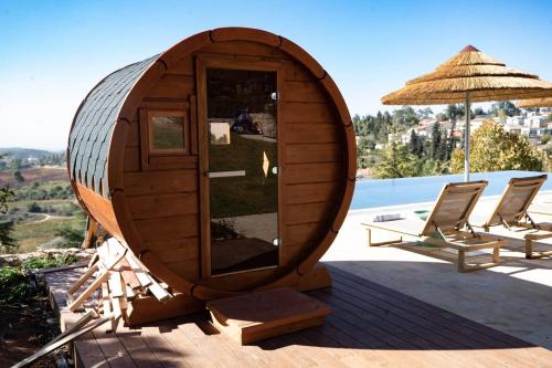 a circular wooden sauna with chairs and an umbrella at Gordonia Ma'ale Hahamisha in Maale Hachamisha
