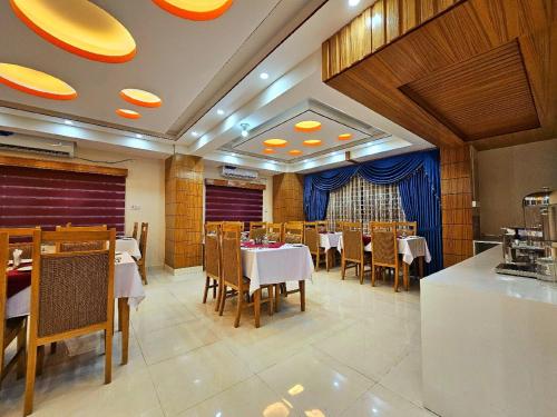 a restaurant with white tables and chairs and blue curtains at Hotel Safa Residency - DHAKA in Dhaka