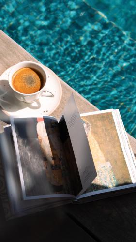 a book and a cup of coffee next to a pool at Gordonia Ma'ale Hahamisha in Maale Hachamisha