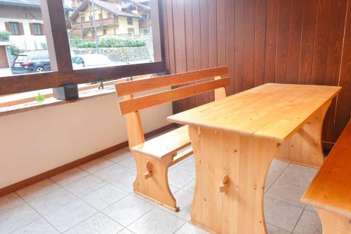 a wooden bench next to a table and a window at Casa Miramonti in Ossana