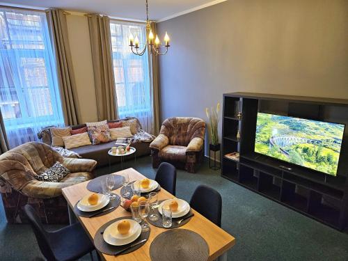 a living room with a television and tables and chairs at Heart of Old Riga 3 Bedroom Apartment by Dome Square in Rīga