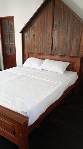 a large bed with a wooden headboard and white sheets at Eleven 11 resort in Tangalle