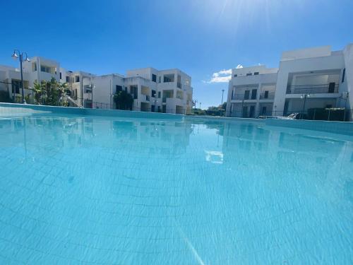 a large blue swimming pool with buildings in the background at San Rocco residence one bed apartments 1A2 4 in Isca sullo Ionio