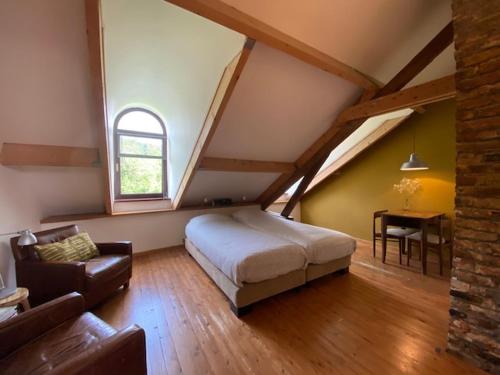 una camera da letto con un letto, un divano e una finestra di B&B van Basten Batenburg a Slenaken