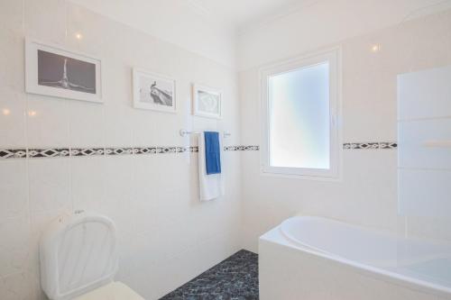 a white bathroom with a toilet and a window at Casa Serena Apartments in Arco da Calheta