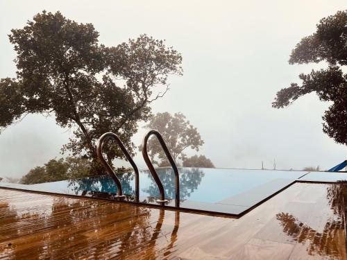 a pool in the rain with trees in the background at Mount Stratus Resort Vayalada in Bālūssheri