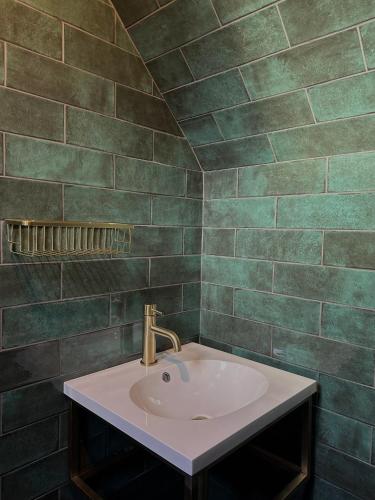 a bathroom with a sink and green tiled walls at Hatton Lodge in Dunkeld