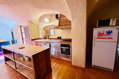 Il comprend une cuisine équipée d'un réfrigérateur blanc et du parquet. dans l'établissement Spacious apartment in village house, à La Salle Les Alpes