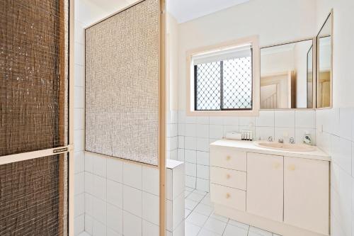 Un baño blanco con lavabo y espejo. en Perfect Waterfront Escape in Surfers Paradise, en Gold Coast
