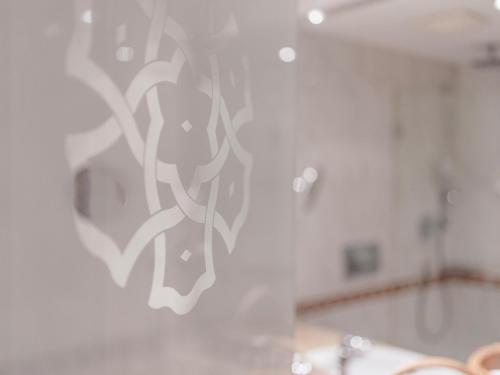 a bathroom with a wall with a design on it at Hotel Norica - Thermenhotels Gastein mit dem Bademantel direkt in die Therme in Bad Hofgastein