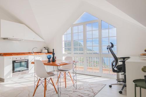 a kitchen with a table and chairs and a large window at Casa Serena Apartments in Arco da Calheta