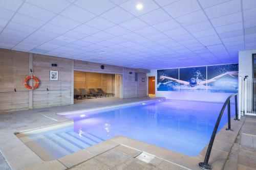 a swimming pool in a building with a painting on the wall at Chalet Alaska Val thorens 130 m2 - Pied des pistes de samedi à samedi in Val Thorens
