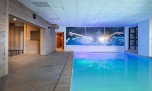 a swimming pool in a building with a painting on the wall at Chalet Alaska Val thorens 130 m2 - Pied des pistes de samedi à samedi in Val Thorens