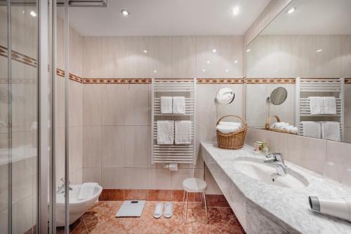 a bathroom with a sink and a shower and a toilet at Hotel Norica - Thermenhotels Gastein mit dem Bademantel direkt in die Therme in Bad Hofgastein