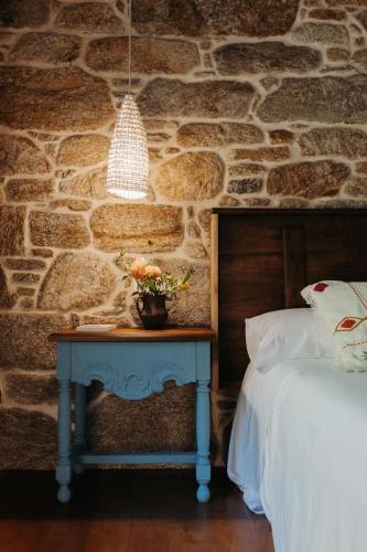a bedroom with a stone wall and a table with a bed at Arrueiro in Laxe
