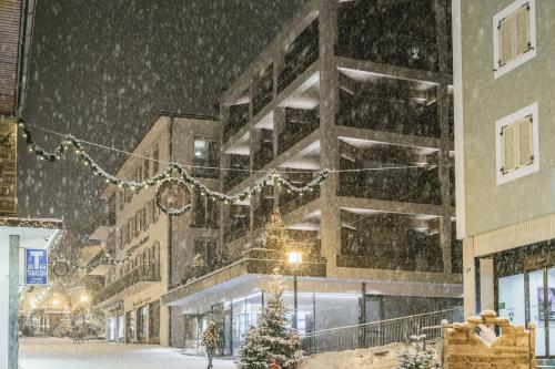 a snow covered street in front of a building at Aquila Dolomites Residence in Ortisei