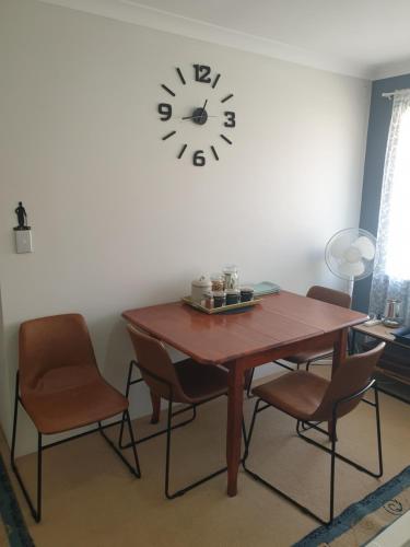 a dining room table with chairs and a clock on the wall at Telperio - Guest suite max 4 Guests in Bunbury