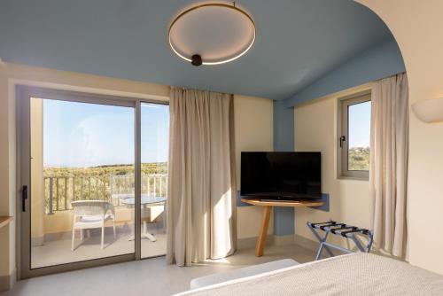 a bedroom with a bed and a television and a balcony at Elia Boutique Hotel in Hersonissos