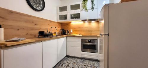 une cuisine avec des armoires blanches et un réfrigérateur en acier inoxydable dans l'établissement EXPO - Paris Porte de Versailles Parc des Expo à 5min avec parking, à Vanves