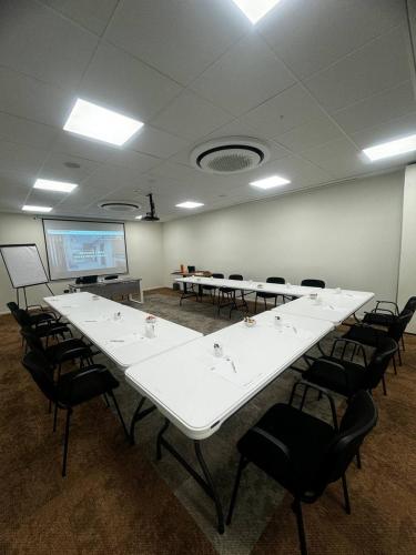 a conference room with white tables and chairs and a projection screen at Acca Sporting Milano - AA Hotels in Opera