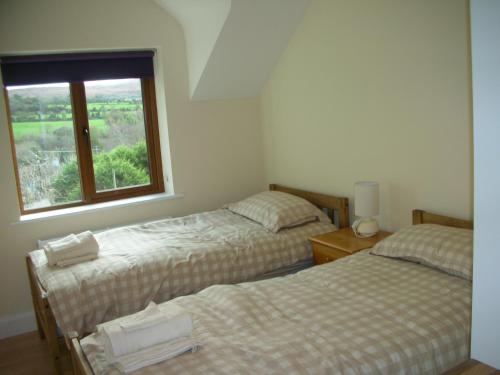 two beds in a room with a window at 18 Carraig Naofa in Bantry