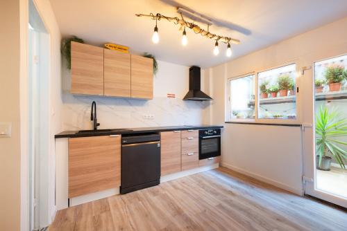 a kitchen with wooden cabinets and a black dishwasher at L'Atelier - Warm Porto Loft in Porto